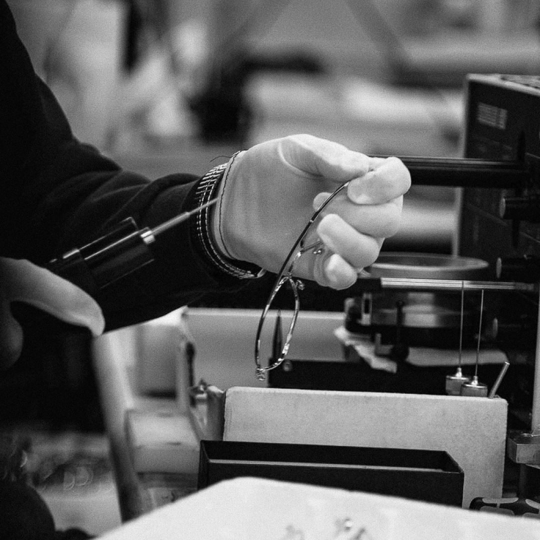Person wearing a glove holding eyeglasses in a workshop setting
